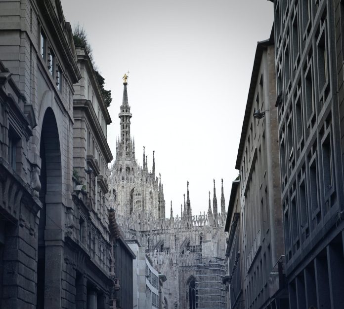 grayscale photo of alley with milan cathedral in background